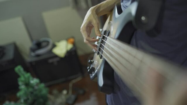 POV shot of Bassist playing electric bass in messy bedroom