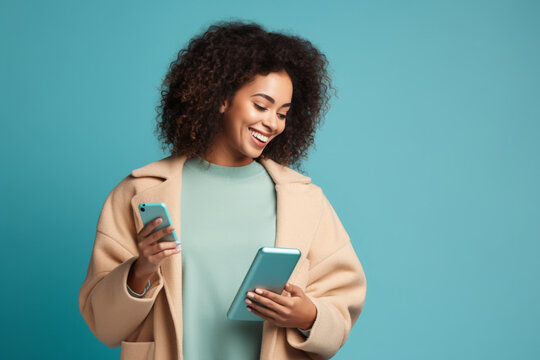 Cheerful woman with shopping bags using mobile phone, Joyful multiracial lady holding purchases and smiling while reading message on smartphone, Isolated on blue background