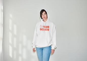 Mockup of woman wearing hoodie with customizable color and hood up, by wall with flash - obrazy, fototapety, plakaty