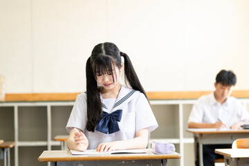 学校の教室で勉強する女子中学生