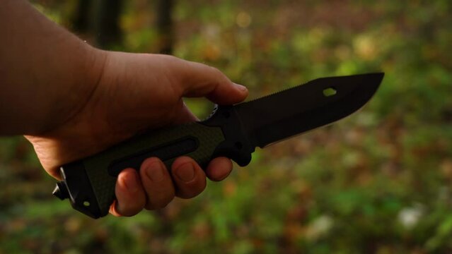 Tourist knife in the hand of a man in the forest