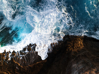 Stormy ocean waves with white foam aerial view hitting rocks in Hawaii