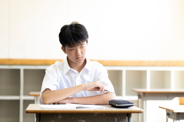 学校の教室で授業を受ける男子生徒