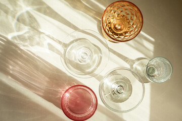 Glasses for wine, champagne, a long shadow from the sun on a light beige background. Wine tasting...