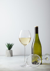 Glass and bottle of white wine on light restaurant background.