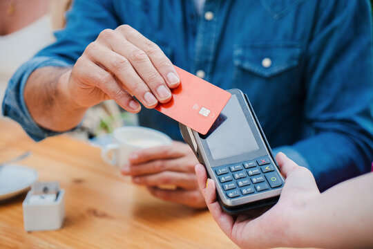 Male customer paying a bill with a contactless credit card in a restaurant. Close up portrait of a man hand holding a creditcard and giving a payment transaction to the cashier. High quality photo