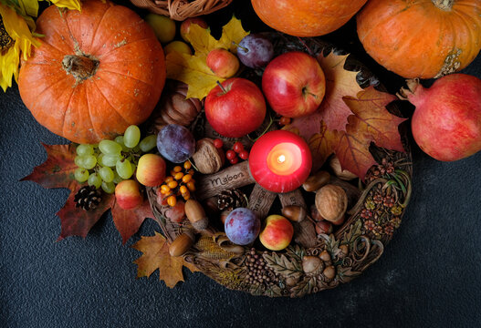 Wiccan altar for Mabon sabbat. fruits, pumpkins, candle, nuts and wheel of the year on abstract dark background. Witchcraft, esoteric spiritual ritual for fall season. symbol of Harvest. top view