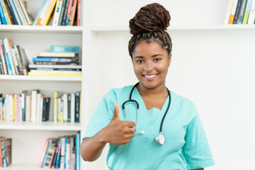 Laughing african american female nurse or medical student showing thumb up