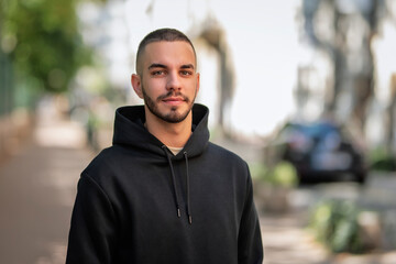 Portrait of a stylish young man standing in a city street and smiling
