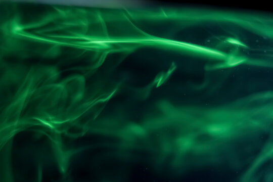 The green liquid that dissolves in water forms an abstract shape.