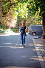 Portrait of blind woman with white cane walking on the street
