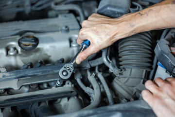 An auto mechanic works with a car engine in the mechanics' garage. Car repair close-up. An authentic close-up shot of an auto mechanic's hands.	