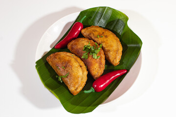 three fried cireng arranged neatly on a plastic plate and decorated with red chilies and a plain...
