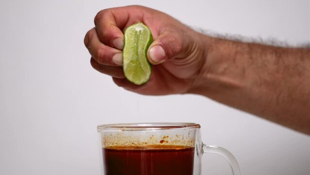 Person squeezing lime into consome birria cup
