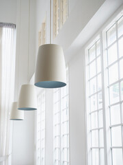 Modern round light lamps cylindrical shape hanging from tall ceiling near the window in minimal...
