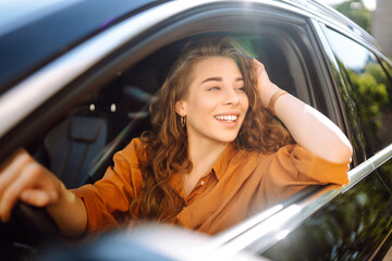 Emotional woman drives a car. Beautiful woman driving a car in the city. The concept of fast...