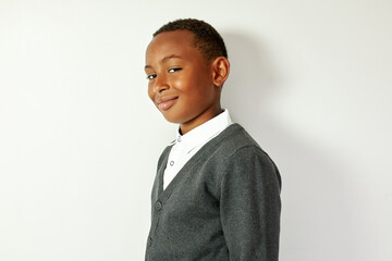 Profile view of cunning sly charismatic black schoolboy turning head to camera smiling...