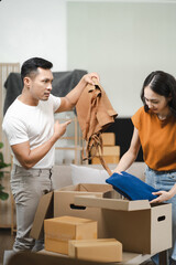 smiling, happy young couple helps put things in boxes and prepares to move into a new house.