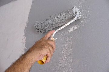 Painting walls with a paint roller. Apartment painting, renovation with gray paint