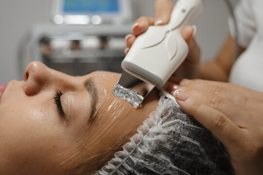 Dermatologist doing ultrasonic facial cleansing on woman's face