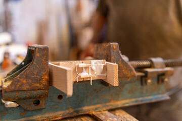 Close-up photo of a glued wooden piece clamped with a workbench vise - Traditional woodworking concept.