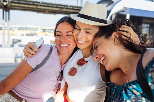 Cheerful friends embracing each other at railroad station platform