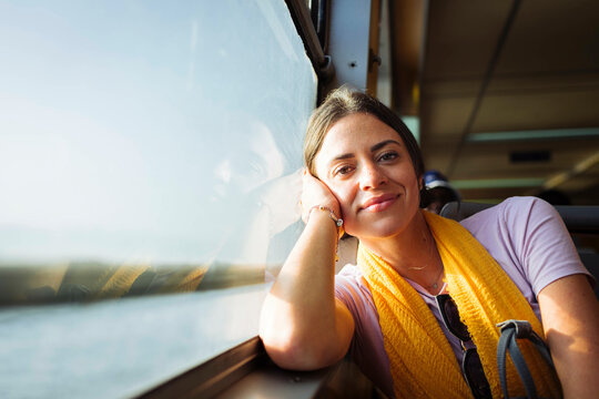Smiling young woman leaning on train window sill