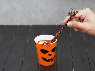 Hand holds coffee paper cup with monster face. Halloween festival background concept. 31 october.