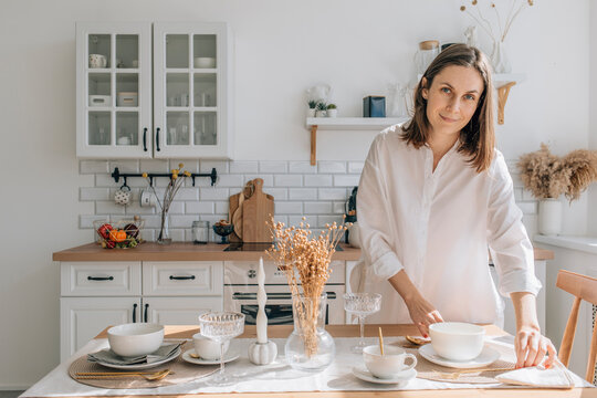 Smiling woman setting dining table in kitchen