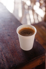 Black hot coffee in a white cup with you on a wooden table