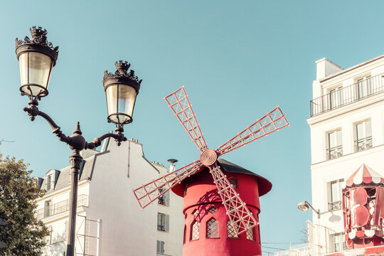 France, Ile-de-France, Paris, Street light in front of red windmill of Moulin Rouge cabaret