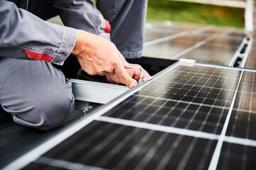 Man technician mounting photovoltaic solar panels on roof of house. Close up view of mounter...