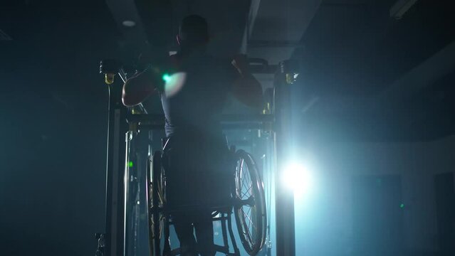 Fortitude, disabled athlete in wheelchair performs pull-ups on the horizontal bar, gym training and physical activity, people with disabilities.