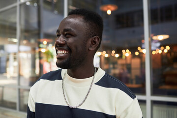 Obraz premium Candid close up portrait of smiling African American man looking away in city, copy space