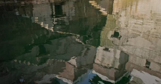 Water storage inside Toorji Ka Jhalra Baoli stepwell, one of water sources in Jodhpur, Rajasthan, India. Sunny day, water riffles reflect walls of the pool. Camera vertical pan