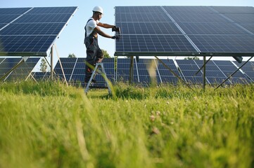 Portrait of african american electrician engineer in safety helmet and uniform installing solar...