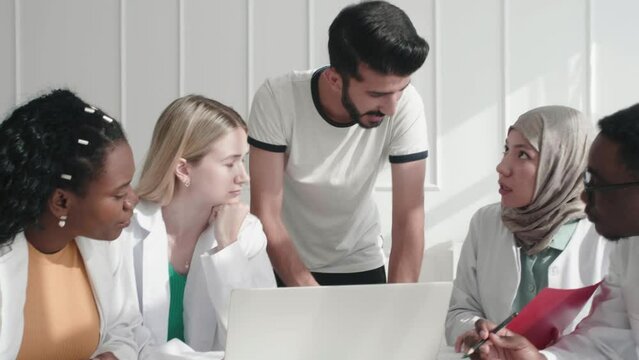 Man Doctor Discussing Patient Case Status With His Team After Operation. Pharmaceutical Representative Showing Medical Report On Digital Laptop About New Medicine Or Therapy. International Doctor Team