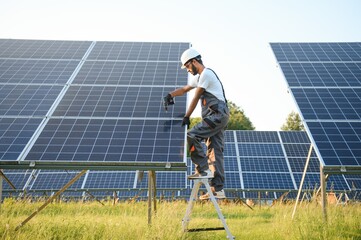 An Indian male worker is working on installing solar panels in a field