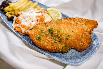 Chicken Escalope with french fries, lemon and salad served in dish isolated on food table top view of middle east spices