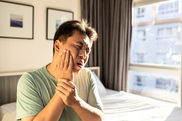 Middle aged man suffer Trigeminal neuralgia,touch his cheek with hand,severe pain of a nerve in face,painful in bulge of cheek and jaw,ache in gum and tooth,feeling like a toothache or tooth decay