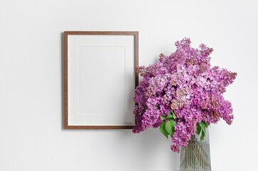 Blank frame mockup with lilac flowers bouquet in white interior, frame mock up with copy space