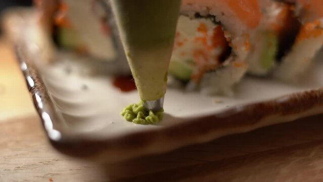 Close-up of a chef putting wasabi paste on a plate of sushi in a restaurant