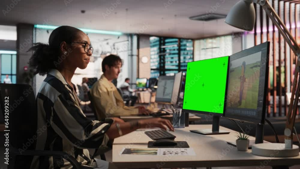 Poster Female Black Game Designer Using Desktop Computer With Green Screen Chromakey on Display, Designing Characters In 3D Modeling Software For Survival Video Game. Woman Working In Game Development Office