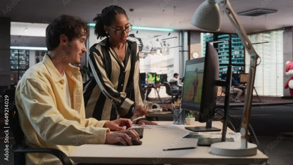 Poster Caucasian Male Game Designer Using Desktop Computer With 3D modelling Software And Talking to Black Female Project Manager in Game Development Studio Office. Diverse Colleagues Discussing New RPG Game
