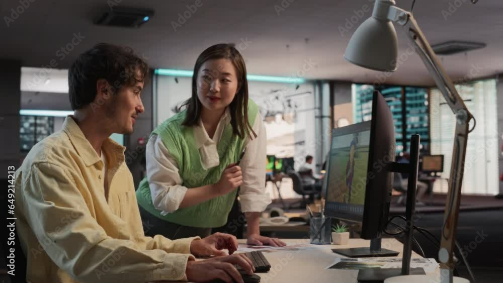 Poster Caucasian Male Game Developer Using Desktop Computer With 3D modelling Software And Talking to Asian Female Project Manager in Game Design Studio Office. Diverse Colleagues Discussing New RPG Game.