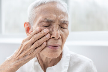 Senior woman touching her face,elderly experiencing pain and numbness in the face,Trigeminal Neuralgia,sudden and severe facial pain,Bell's palsy symptom,facial muscle weakness or paralysis,healthcare - obrazy, fototapety, plakaty