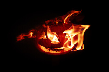 Halloween pumpkin fire smile and scary eyes for party night. Close up view of scary Halloween pumpkin with fire eyes at black background. Soft focus