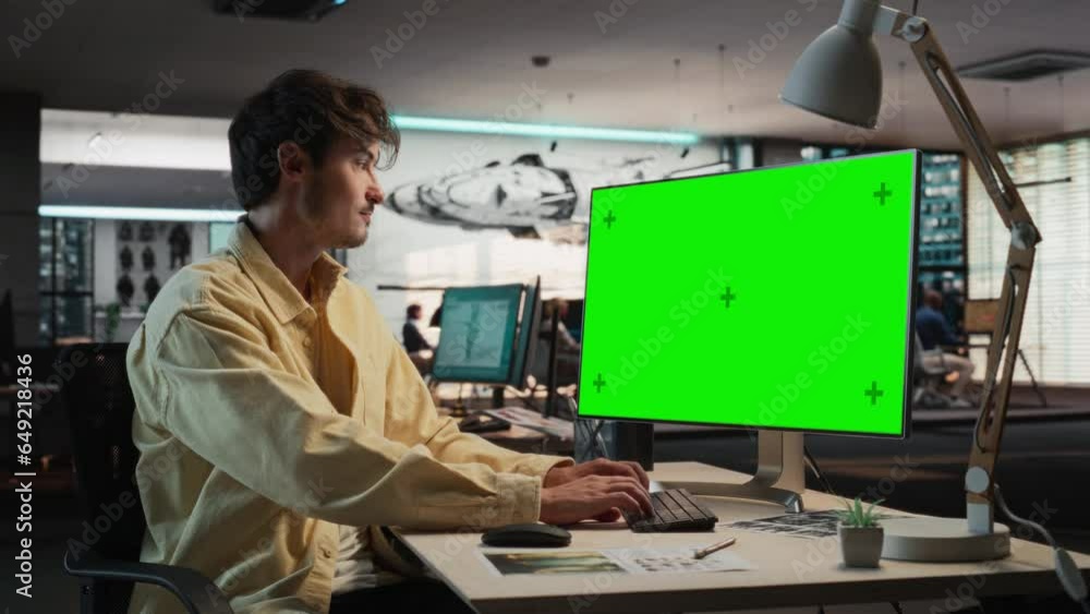 Leinwandbilder Caucasian Man Using Desktop Computer with Mock-up Green Screen Chromakey. Male Concept Artist Working in Game Design Startup Diverse Office, Creating Immersive Gameplay For New Survival Video Game.