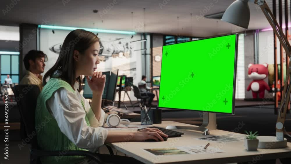 Poster creative asian woman sitting at her desk using desktop computer with mock-up green screen chromakey.