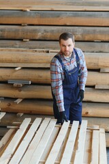 Builder holds wooden planks. Concept - sale of lumber. Builder is considering wood planks. Concept - wood processing business. wood timber stack of wooden planks.